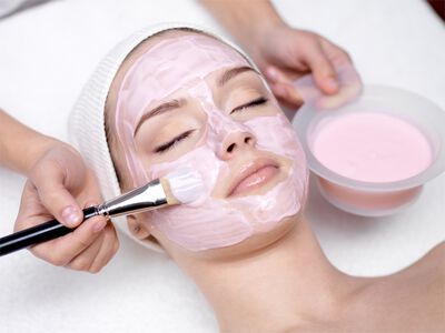 Frauengesicht auf das mit Pinsel eine Gesichtsmaske aufgetragen wird